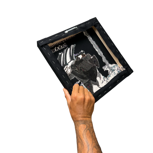 Hand holding a black framed artwork with a white background